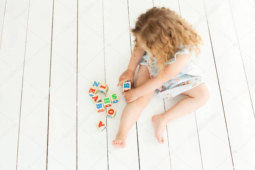 Little cute girl playing with abc cubes and educating. Pretty gi