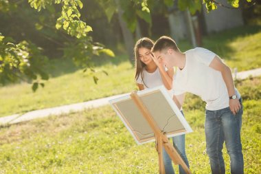 Genç çift, şövale çizerek renkli alacalı boyalar. Öncesi