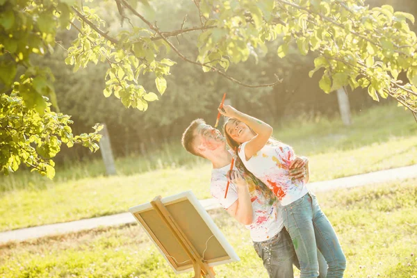 Jovem casal bonito se divertindo ao ar livre com pinturas. Bonito. — Fotografia de Stock