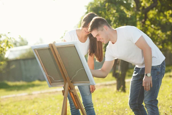 Pareja joven dibujando en caballete por coloridas pinturas variadas. Antes de — Foto de Stock