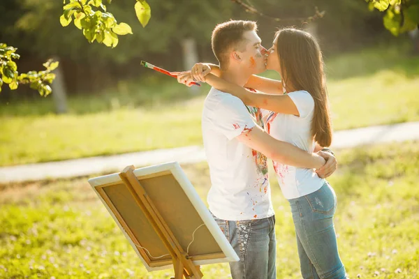 Jovem casal bonito se divertindo ao ar livre com pinturas. Bonito. — Fotografia de Stock