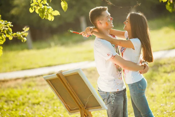 Jovem casal bonito se divertindo ao ar livre com pinturas. Bonito. — Fotografia de Stock