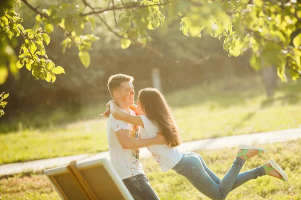 Joven pareja bonita divirtiéndose al aire libre con pinturas. Guapo. — Foto de Stock