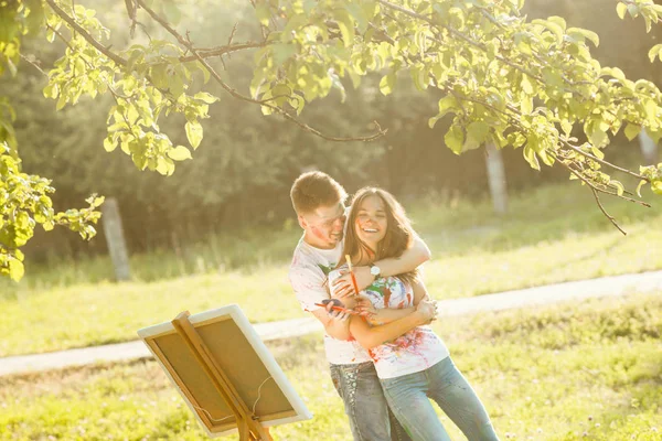 Jovem casal bonito se divertindo ao ar livre com pinturas. Bonito. — Fotografia de Stock