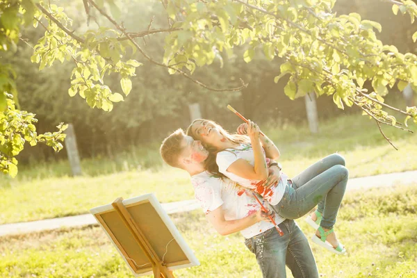 Young pretty couple having fun outdoors with paintings. Handsome