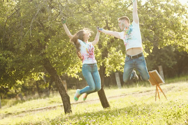 Smiling pretty couple jumping taking each other by the hand. Bea — Stock Photo, Image