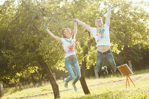 Smiling pretty couple jumping taking each other by the hand. Bea — Stock Photo, Image