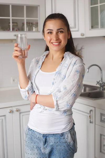 Jovem mulher bonita de pé na cozinha com vidro de pu limpo — Fotografia de Stock