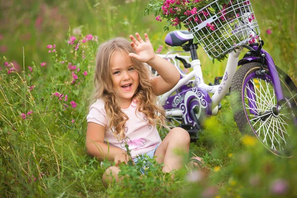 Küçük şirin kız Bisiklet l yakınındaki çiçek alan dinlenme — Stok fotoğraf