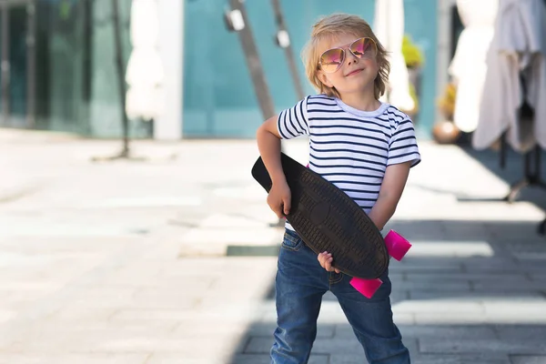 Um rapazinho bonito num skate. Miúdo emocional ao ar livre. Bonito. — Fotografia de Stock