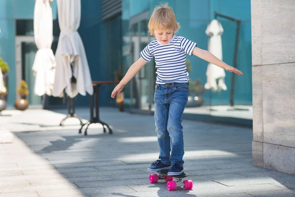 Um rapazinho bonito num skate. Miúdo emocional ao ar livre. Bonito. — Fotografia de Stock