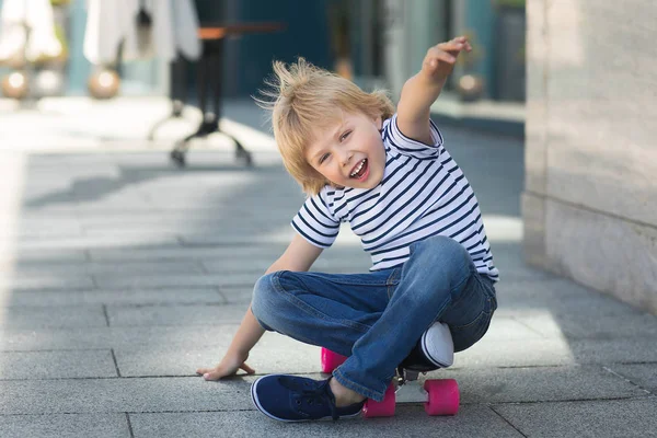 Um rapazinho bonito num skate. Miúdo emocional ao ar livre. Bonito. — Fotografia de Stock