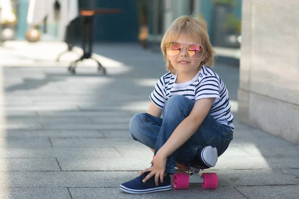 Um rapazinho bonito num skate. Miúdo emocional ao ar livre. Bonito. — Fotografia de Stock