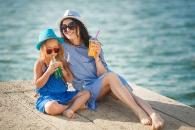 Genç anne ve limonata içmeye yatak üzerinde oturan kız