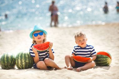 Deniz kıyısında oturan ve taze karpuz yeme iki erkek