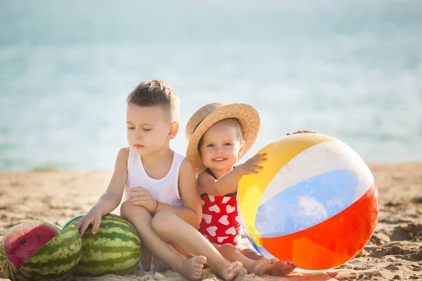 少年とスイカに水の近くのビーチに座っている女の子 — ストック写真