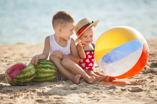 少年とスイカに水の近くのビーチに座っている女の子 — ストック写真