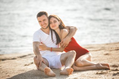 Genç çift sahilde günbatımı eğleniyor