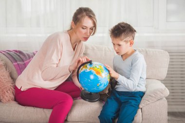 Anne ve oğlu evde seyahat yeri seçme küre ile oynamak