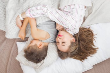 Anne ile oğlu beyaz battaniye altında yatakta yatmak 