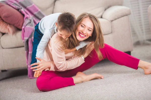 若い母親は家のリビング ルームの床に息子と遊ぶ — ストック写真