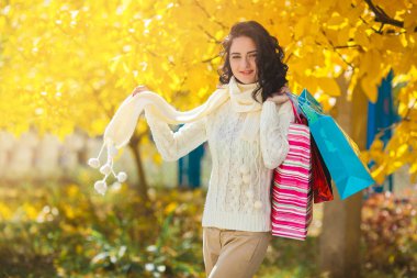 Alışveriş yaparken neşeli genç kadın. Güzel kız alışveriş torbaları ile sonbahar arka plan açık açık havada.