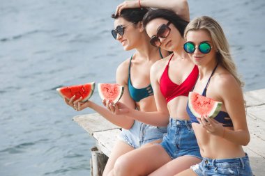 Karpuz yeme ve güneş zevk iskelede eğleniyor genç neşeli kız grubu