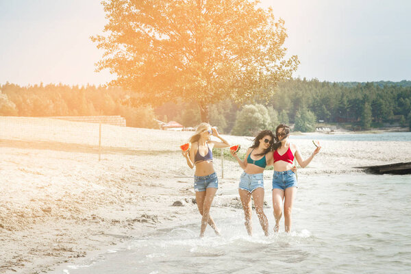 Girlfriends on the beach eating watermelon and enjoying sun