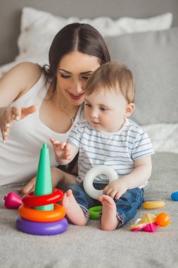 Küçük oğluyla birlikte oynayan genç güzel anne. Neşeli aile kapalı küçük bebek oğlu ile eğleniyor