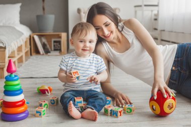 Küçük oğluyla birlikte oynayan genç güzel anne. Neşeli aile kapalı küçük bebek oğlu ile eğleniyor