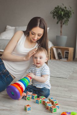 Küçük oğluyla birlikte oynayan genç güzel anne. Neşeli aile kapalı küçük bebek oğlu ile eğleniyor
