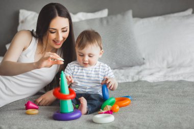 Küçük oğluyla birlikte oynayan genç güzel anne. Neşeli aile kapalı küçük bebek oğlu ile eğleniyor
