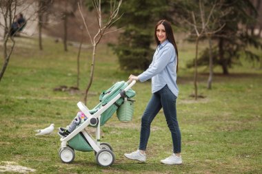 Genç neşeli anne çocuğunu carriege ile yürüme