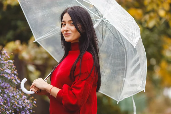 Cheerful young woman with umbrella in autumn park