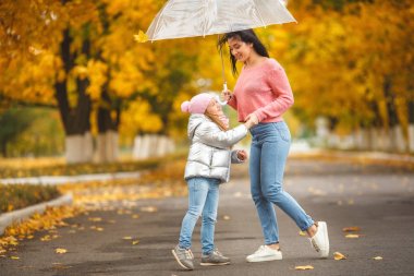 Genç Anne ile küçük kızı sonbahar arka planda eğleniyor güzel. Mutlu aile Güz