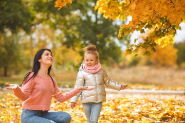 Neşeli kızlar sarı yaprakları ile oynuyor. Mutlu anne ve eğleniyor sonbahar zamanla küçük çocuk