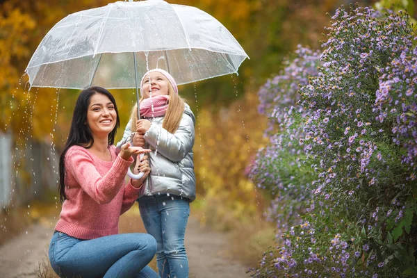 可爱的孩子与她的年轻母亲在秋季背景下的雨伞乐趣 愉快的家庭在秋天时间 — 图库照片