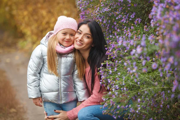 Young beautiful mother spending time with her little cute daughter in the fall time