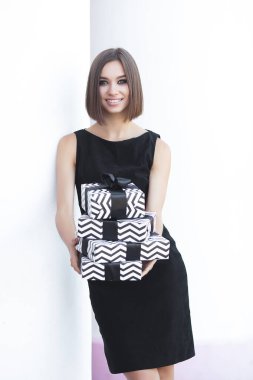 Siyah elbiseli şık bir kadın. Kara Cuma konsepti. Elinde hediyeler olan bir kadın..