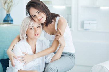 Anne ve yetişkin kız evde birlikte. Evde mutlu bir aile. Yetişkin bir anne ve yetişkin kızı takılıyor..