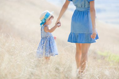 Genç ve çekici annesi ve küçük tatlı kızı dışarıda eğleniyorlar. Yazın mutlu bir aile. Annem ve onun güzel çocuk portresi..