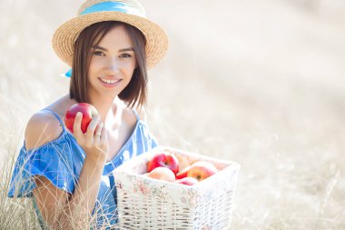 Yaz geçmişinde çekici bir genç kadın. Gülümseyen kadın portresi. Güzel bayan dışarıda elma tutuyor..