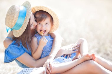 Genç ve çekici annesi ve küçük tatlı kızı dışarıda eğleniyorlar. Yazın mutlu bir aile. Annem ve onun güzel çocuk portresi..