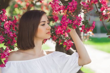 Çiçekli arka planda güzel bir bayan. Çiçekli kadın. Pembe çiçekli muhteşem bir kadın poretosu..