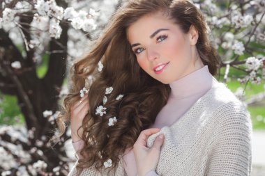 Bahar arka planında güzel bir bayan. Saçında çiçekler olan bir kadın. Doğuştan güzel geçmişi olan bir kadın..