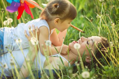 Baharda mutlu anne ve küçük çocuğunun portresi. Karahindiba tarlasında neşeli bir aile. Anne ve tatlı kızı dışarıda..