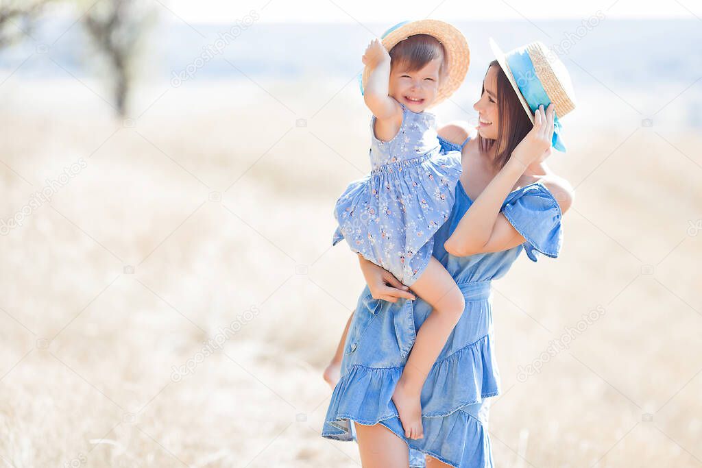Young attractive mother and her little cute daughter having fun outdoors. Happy family at summer.Mom and her beautiful child portrait.