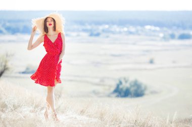 Doğal arka planda çekici genç bir kadın. Kırmızı elbiseli ve kırmızı rujlu bir bayan. Güzel bir kadın modelin yakın portresi..