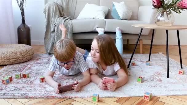 小さなかわいい子供たちがスマートフォンを遊んでいる 兄弟姉妹 ホームビデオゲームをプレイ — ストック動画