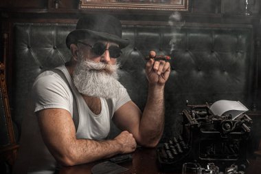 Yaşlı adam içeride puro içiyor. Mafya konsepti. Dolabında şık bir erkek. Sakallı adam..